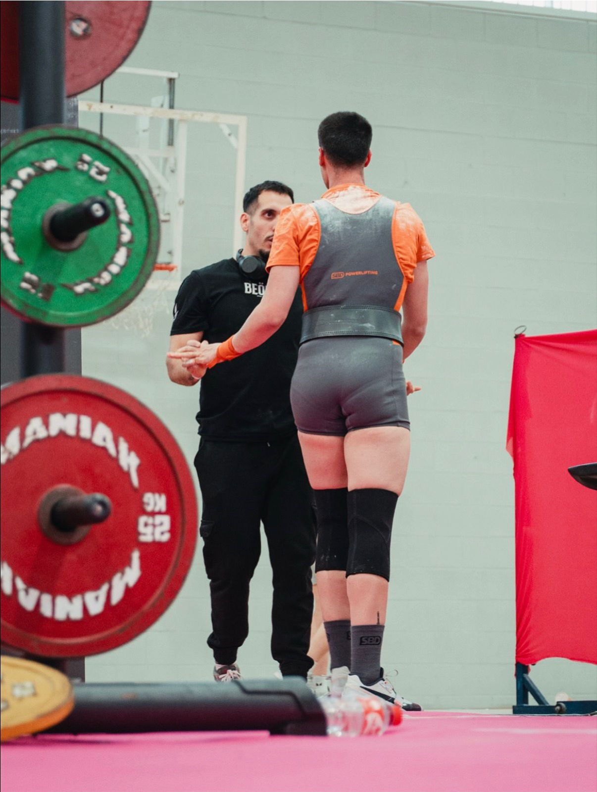Manu dando indicaciones a un atleta con camiseta naranja durante una competición